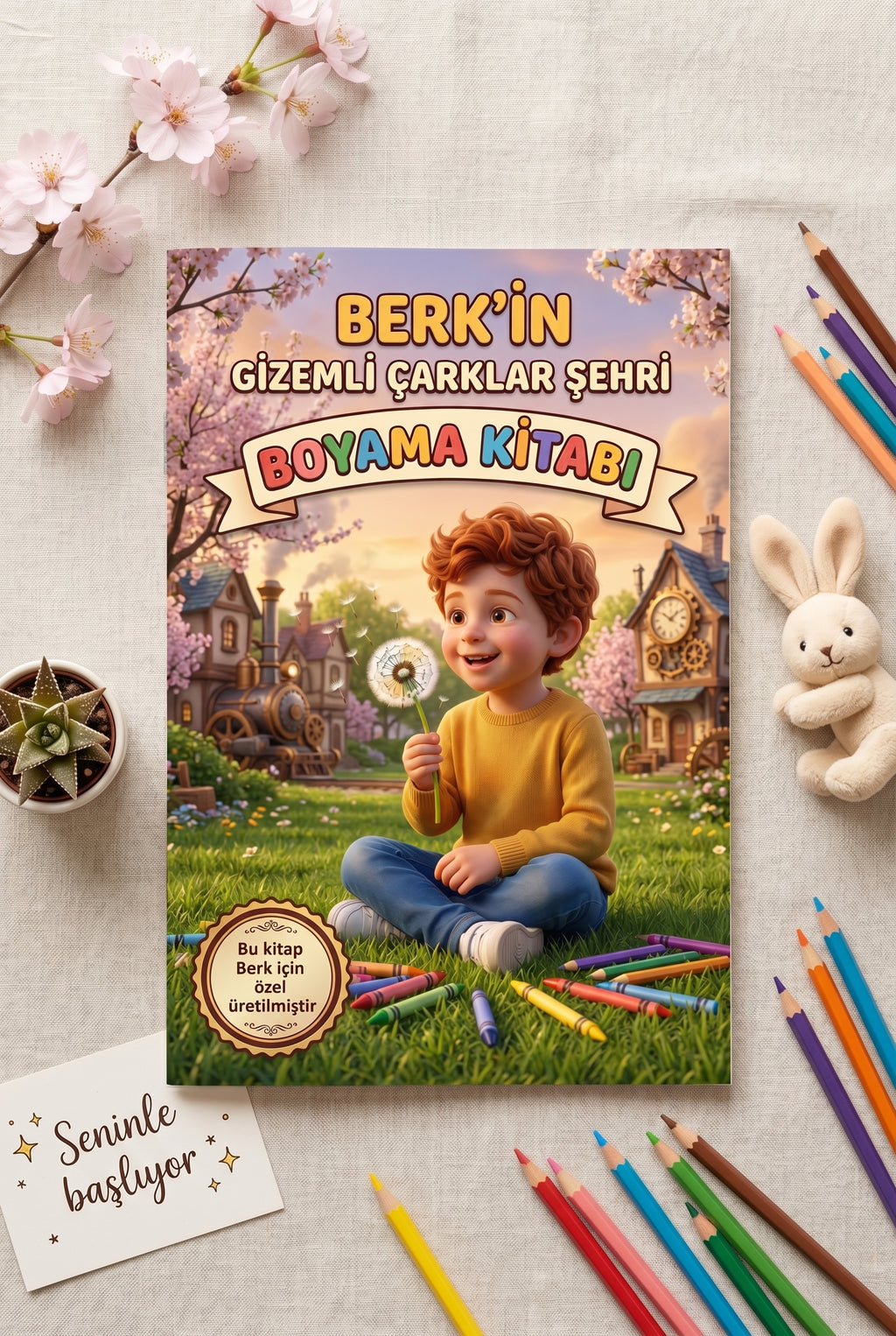 Masanın üzerinde duran Berk'in kişiye özel kitabı, boya kalemleri ve mekanik kuş maketi