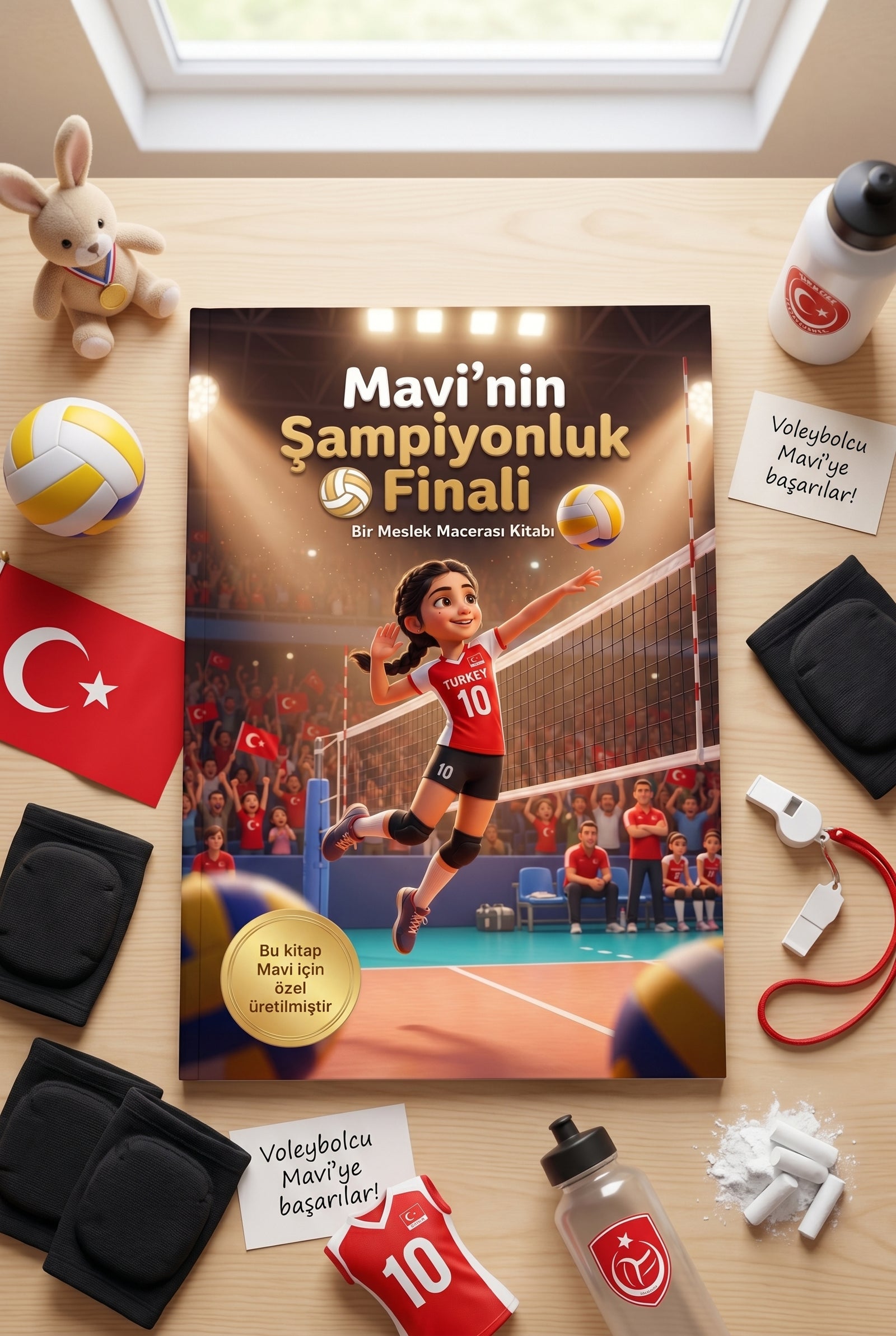 Ahşap zemin üzerinde Mavi'nin Şampiyonluk Finali kişiselleştirilmiş hediye kitabı, voleybol topu ve çocuk dizlikleri.